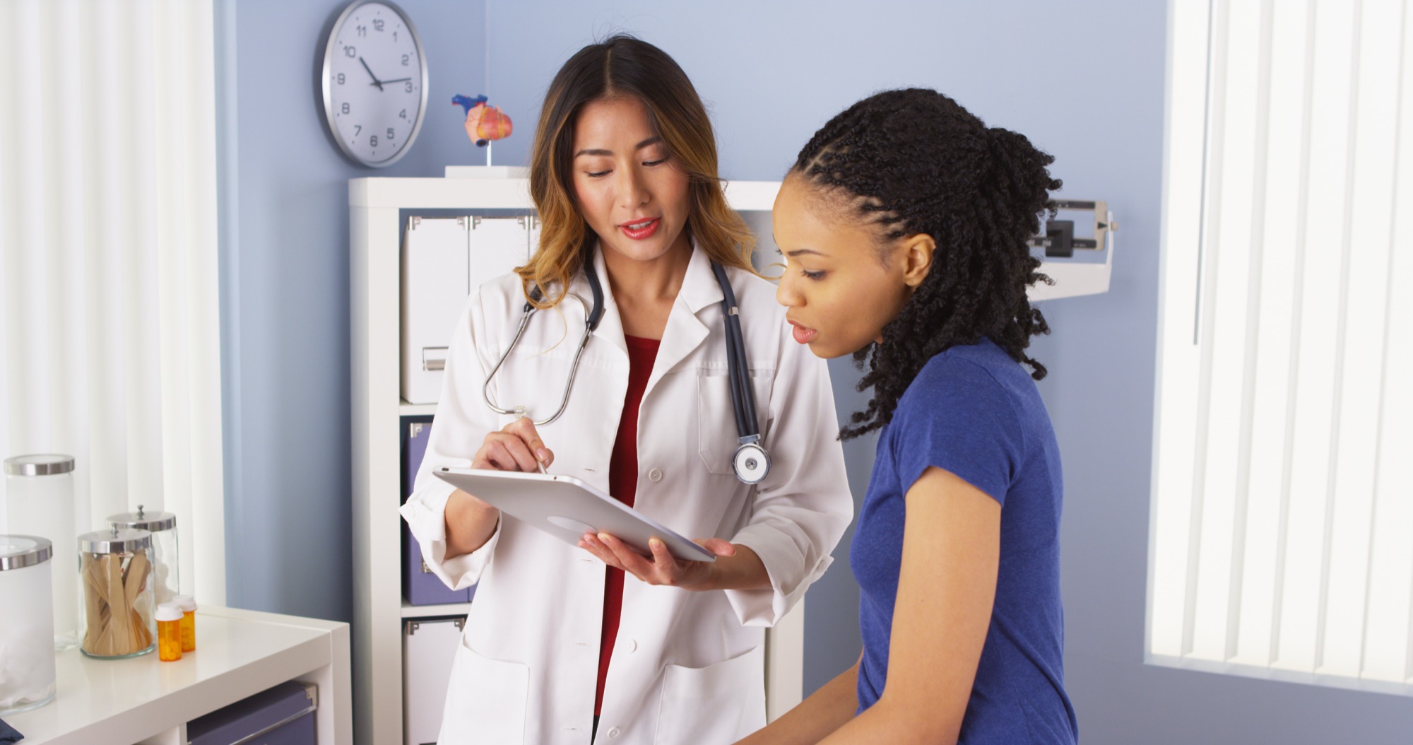 A patient discusses health information with a clinician using a tablet.